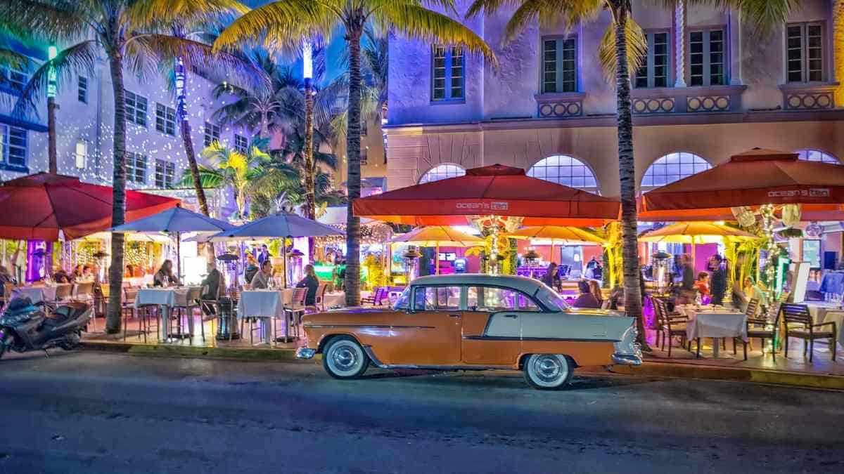 A yellow classic car on Miami's Ocean Drive at night