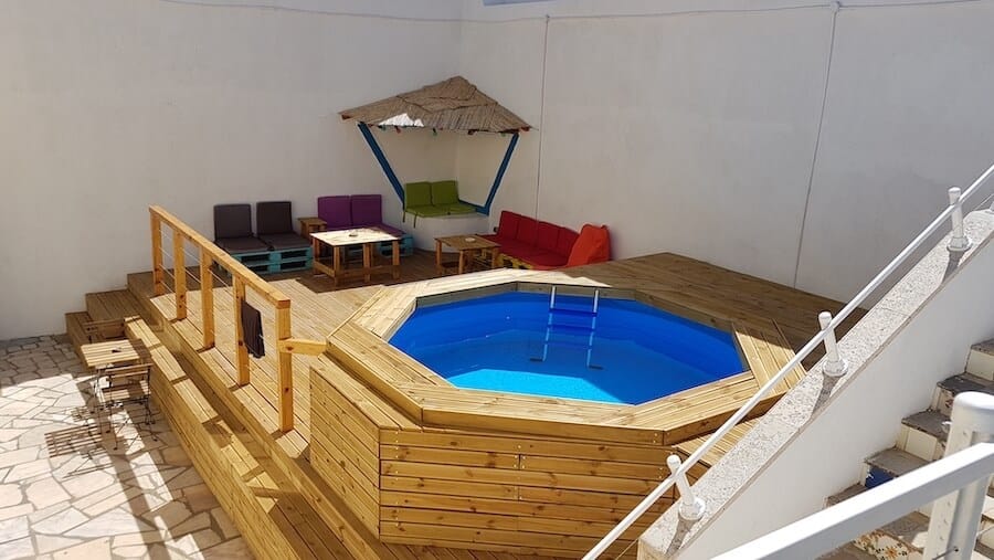 The swimming pool and outdoor seating in the common area at Surfer's Den Ericeira Hostel in Portugal, one of the best hostels in Europe