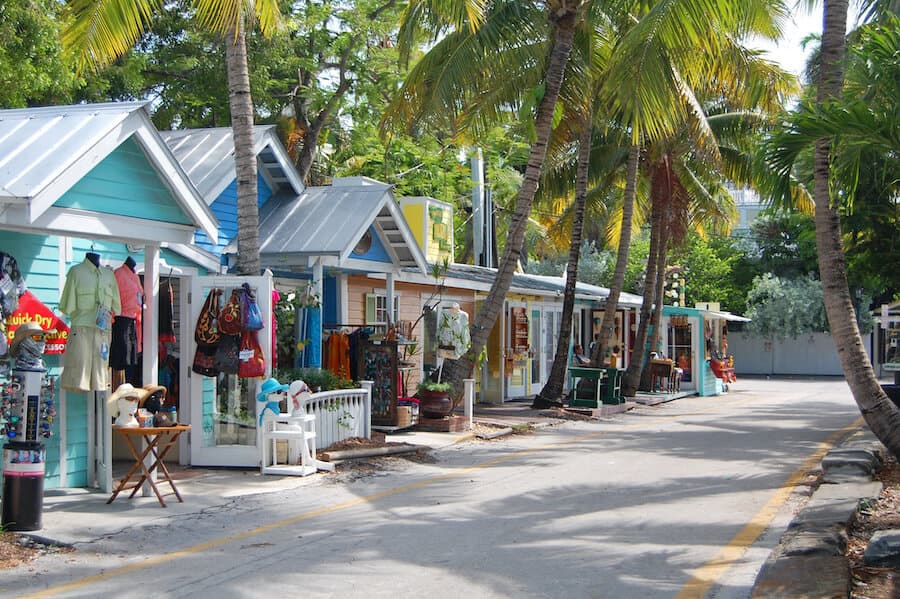 Quaint and colorful boutique shops line a peaceful street in Key West, Florida, nestled among lush palm trees, offering a vibrant shopping experience in one of the best spring break destinations for college students.