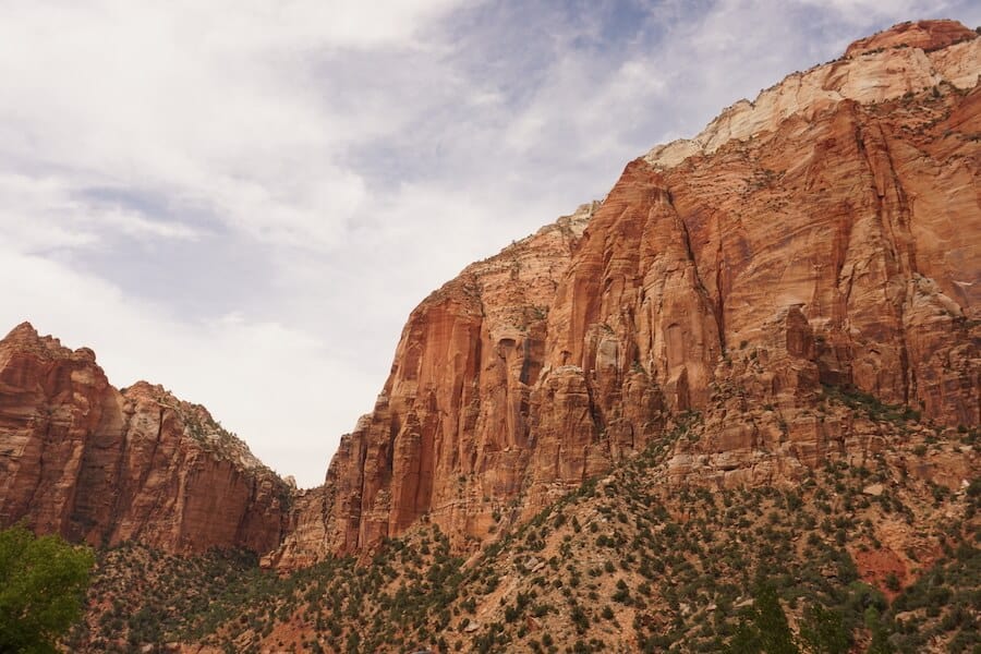 Majestic red sandstone cliffs under a partly cloudy sky at Zion National Park, Utah, showcasing the natural beauty and rugged landscape ideal for adventurous college spring break explorations.