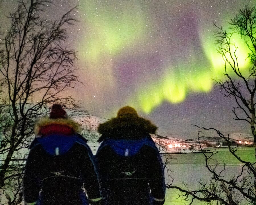 Two travelers in winter gear seeing the Northern Lights in Tromso Norway