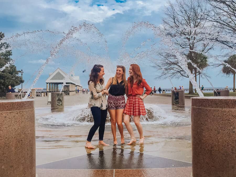 3 girl friends standing and laughing in a fountain in Charleston, South Carolina