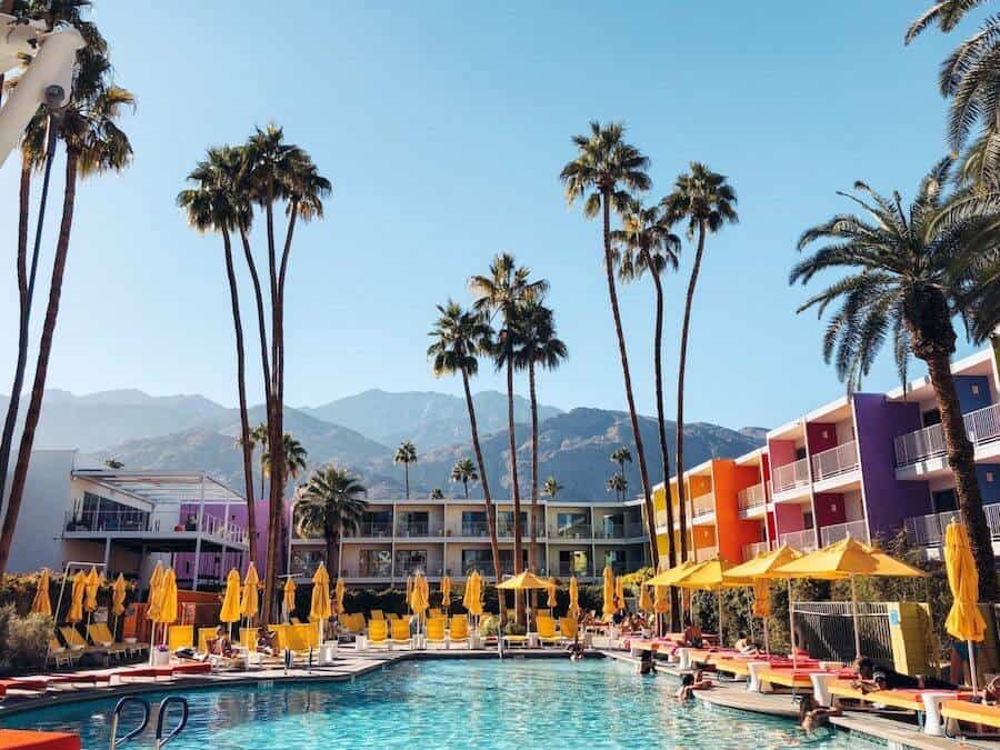 Swimming pool with palm trees and yellow beach chairs at a hotel in Palm Springs California