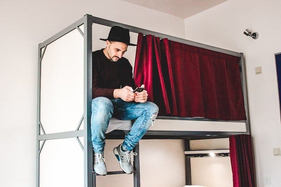 A guy sitting on the top bunk of a bunk bed at St. Christopher's Inn Berlin Mitte hostel.