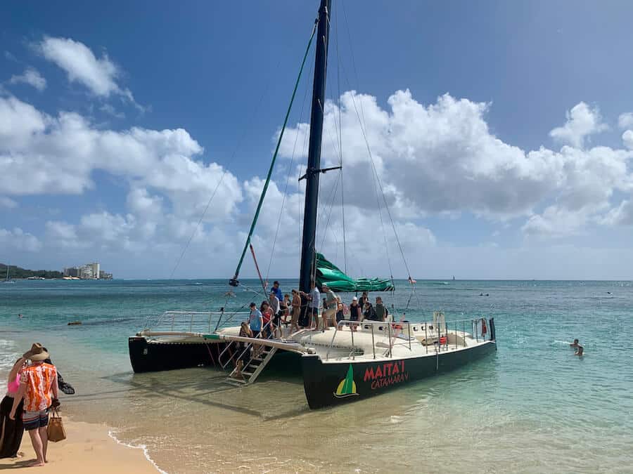 Passengers boarding a catamaran boat in the water off the coast of Waikiki Beach