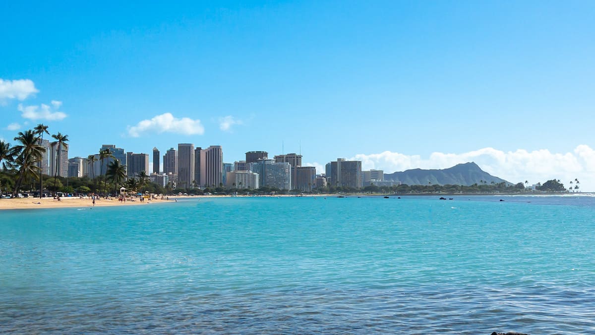A view of Waikiki Beach from the blue water, with Diamond Head's peak far in the distance